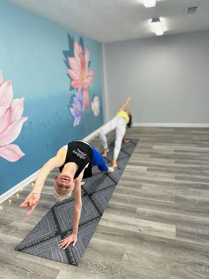 A student in a flowing yoga pose in front of the lotus mural