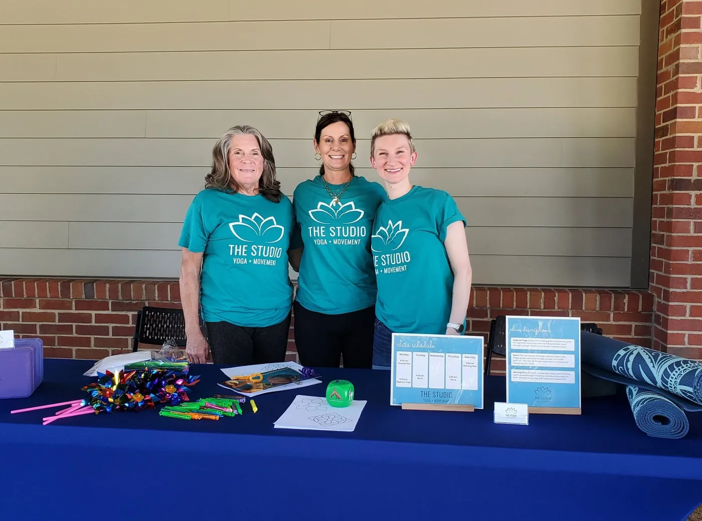 Teachers from The Studio in teal studio shirts at a community event