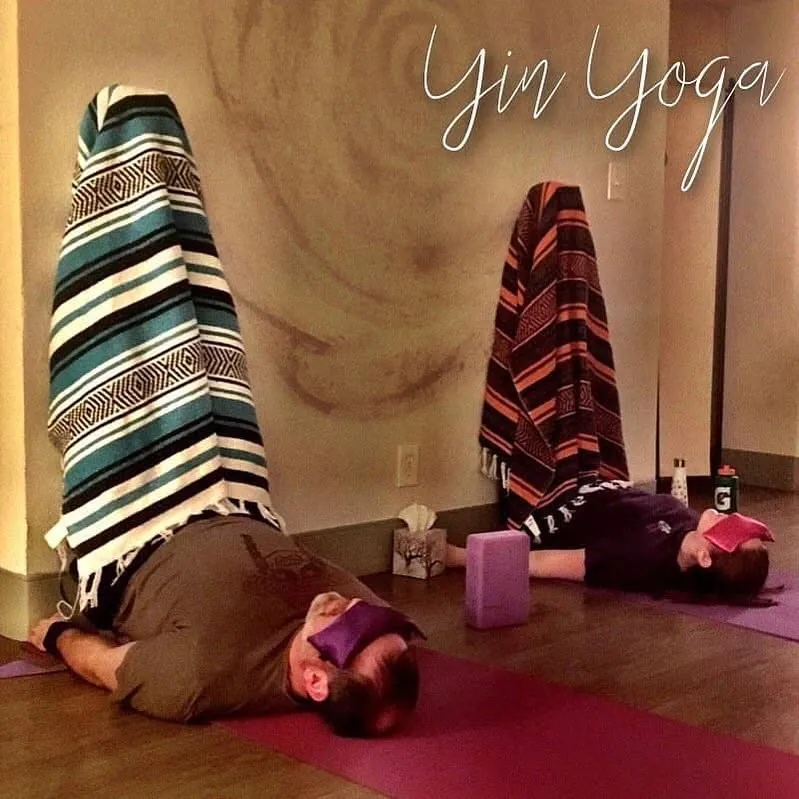 Students resting in supported yin yoga poses with legs up the wall